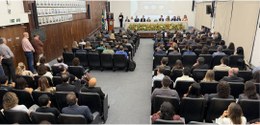 Foto mostra o auditório do TRE-MG, com a plateia lotada. Ao fundo, o desembargador Carlos Henriq...