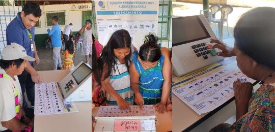 Diversos indígenas observam cartazes colados na parede de uma escola.