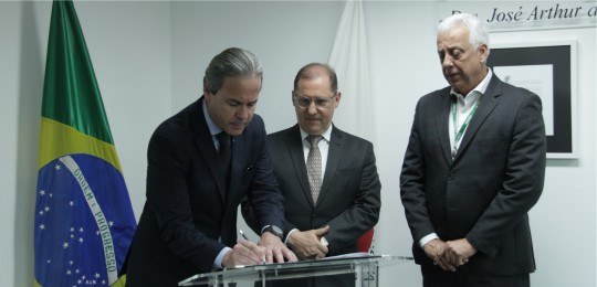 TRE e Cemig assinam terno de cooperação para as Eleições 2022 Desembargador Maurício Soares assina um documento, observado por dois representantes da Cemig