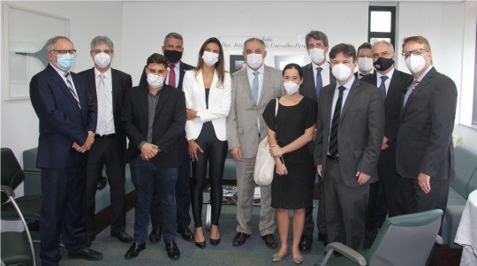 Nove homens e duas mulheres, todos usando máscara de proteção facial, posam para a foto. O desem...