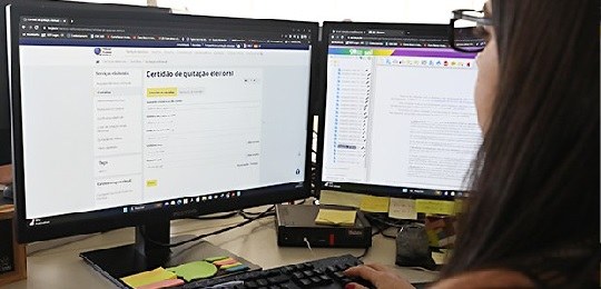 Foto de uma pessoa com duas telas de computador