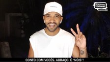 Foto do rapper Flávio Renegado. Ele olha para a câmera sorrindo e faz um sinal de "V" com a mão ...