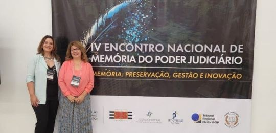foto de duas servidoras do TRE-MG à frente de um painel do IV Encontro Nacional de Memória