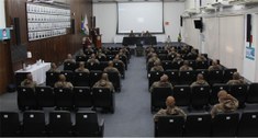 Foto do auditório do TRE, mostrando policiais militares sentados na plateia e três homens sentad...