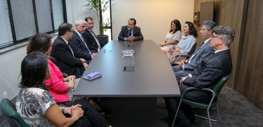 TRE-MG-parceria-violencia-politica-de-genero Foto com dez pessoas sentadas em torno de uma mesa de reuniões