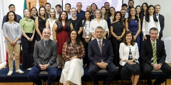 Foto dos novos servidores que tomaram posse, tendo a frente sentados autoridades do TRE-MG