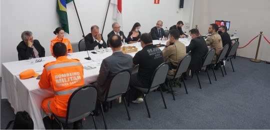 Foto de várias pessoas sentadas ao redor de uma mesa durante uma reunião.