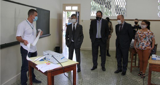 Foto de alguns homens e uma mulher em uma sala de aula, observando um homem segurando uma longa ...