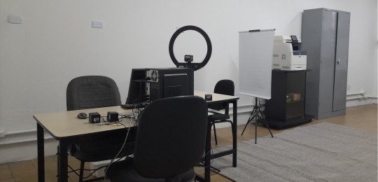 Foto mostra a estação de atendimento ao eleitor. Duas mesas com alguns equipamentos de informáti...