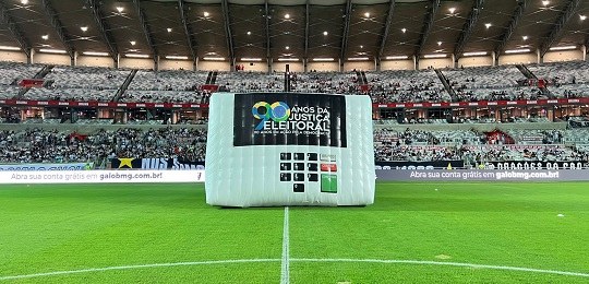 Foto de uma urna eletrônica gigante no gramado do estádio Mineirão.