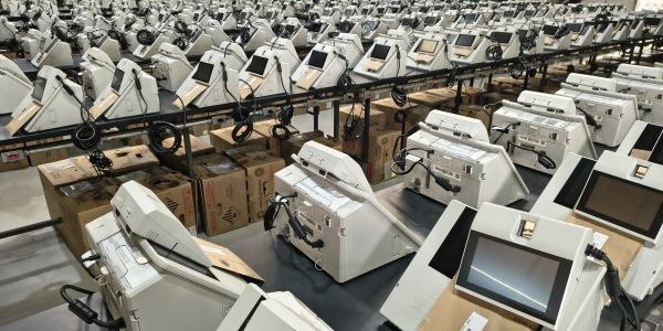 Foto mostra dezenas de urnas eletrônicas sobre bancadas