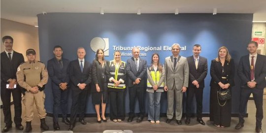 Autoridades posam para a foto. Atrás delas, uma parede azul com a inscrição Tribunal Regional El...
