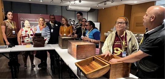 Foto mostra homens e mulheres cegos tocando urnas de madeira