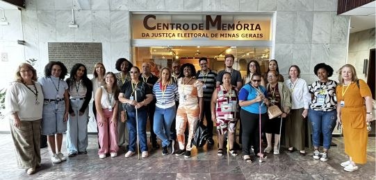 Homens e mulheres posam para a foto em frente ao Centro de Memória do TRE-MG
