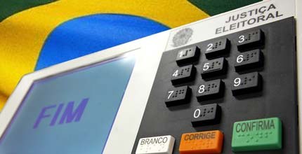 TRE-BA-Urna eletronica Imagem da urna eletrônica com a bandeira do Brasil atrás.