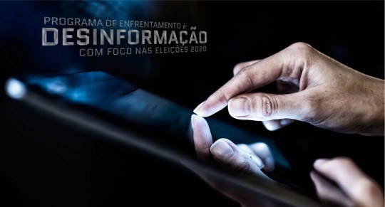 Foto de uma mão masculina tocando a tela de um dispositivo que parece ser um tablet. O fundo da ...